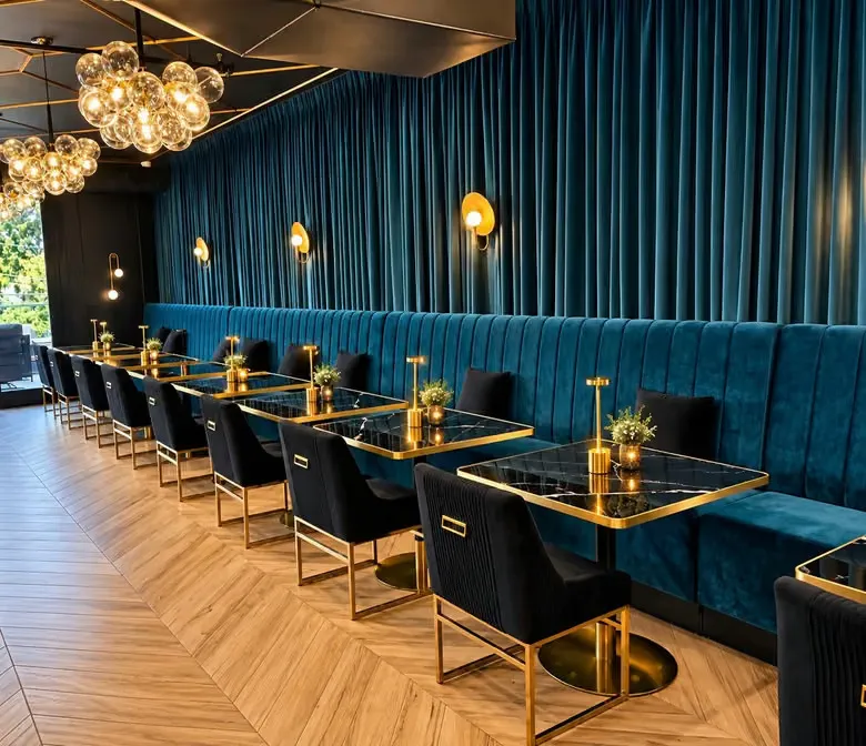 Interior of the Il Vero restaurant, featuring blue velvet booth seating, black and gold tables, and modern lighting.