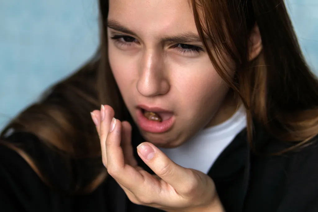 A young girl experiences nausea and spits food out into her hand.