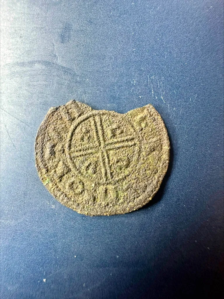 A damaged Anglo-Saxon coin dating to the late 10th century, featuring a central cross design.