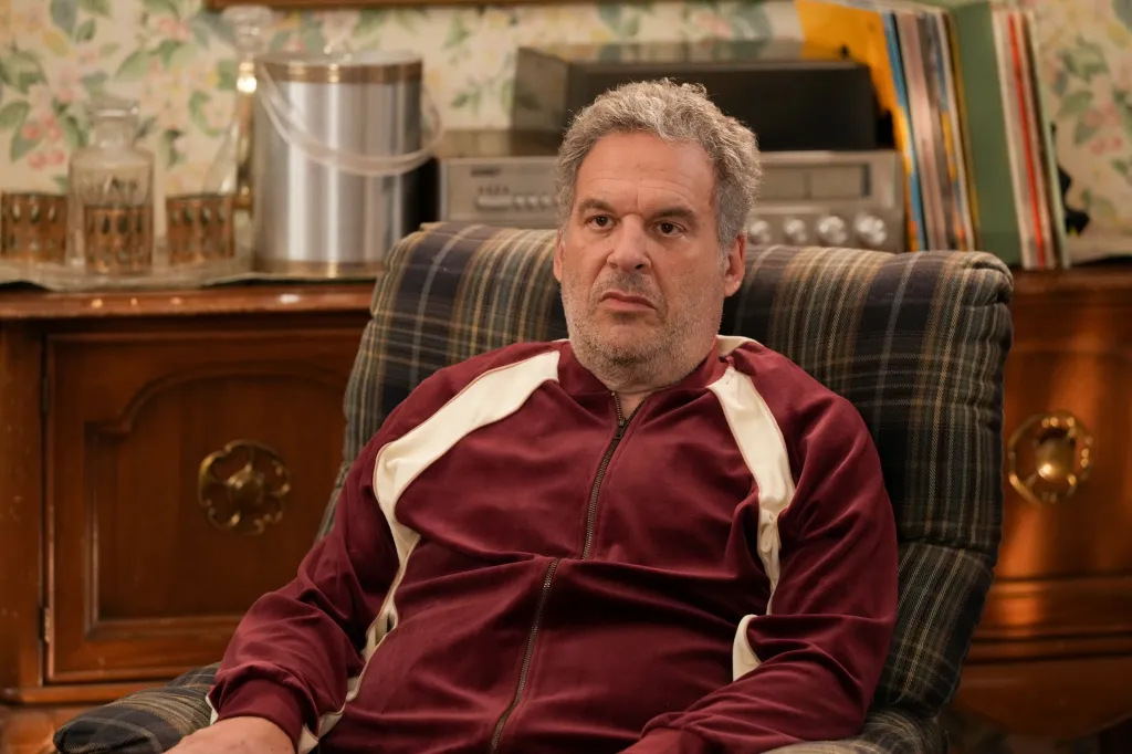 Jeff Garlin as Murray Goldberg sitting in a plaid armchair in The Goldbergs.