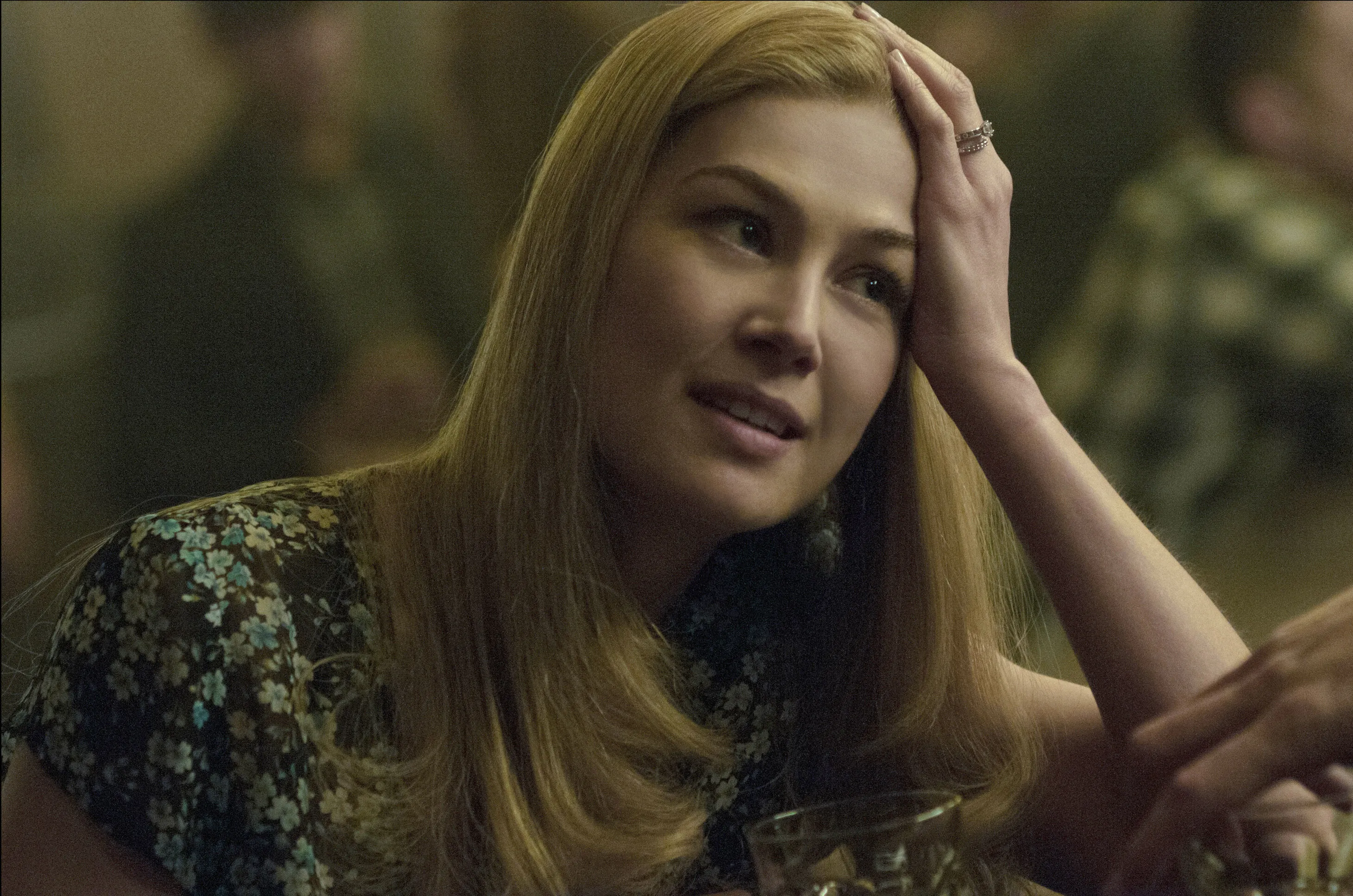 Rosamund Pike as Amy Dunne in Gone Girl, holding her head with her hand.