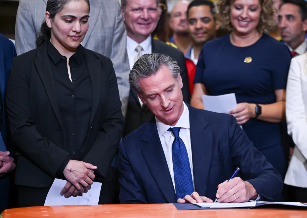 California Governor Gavin Newsom signs legislation addressing property crime, surrounded by supporters.