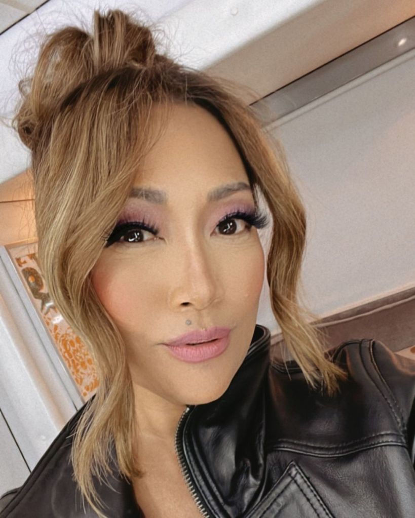 Carrie Ann Inaba wearing a black leather jacket and her hair in a top knot.