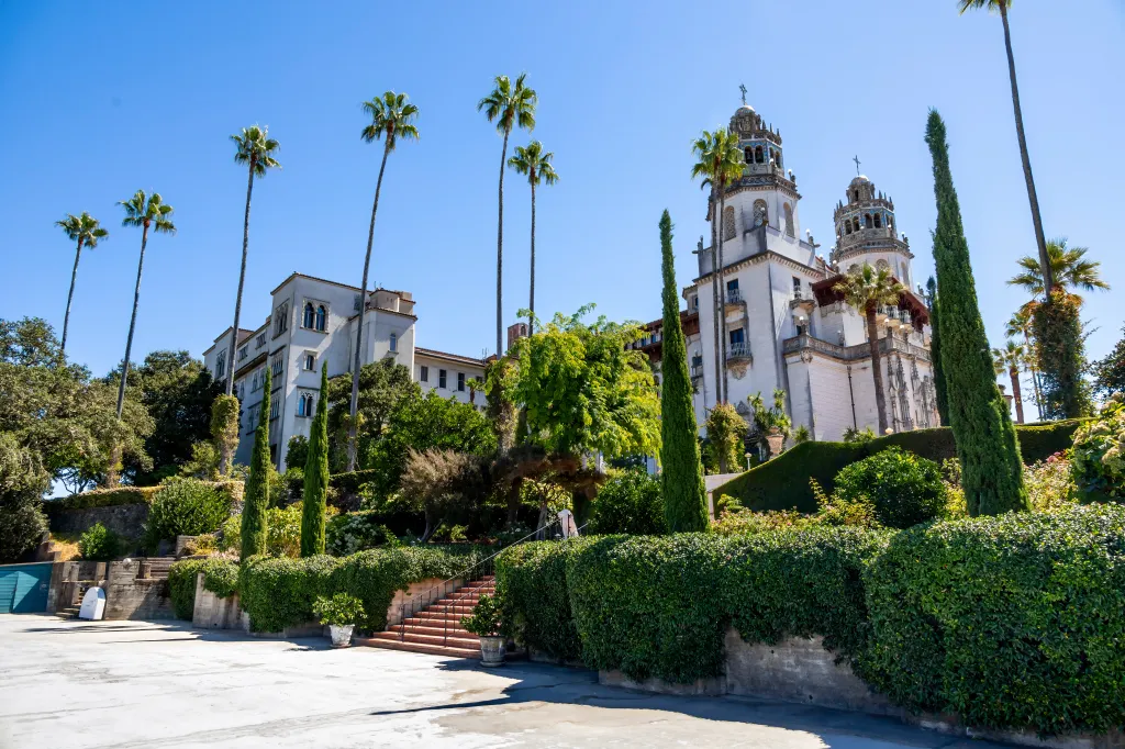 Exterior of Hearst Castle with its gardens and towers under a clear blue sky.