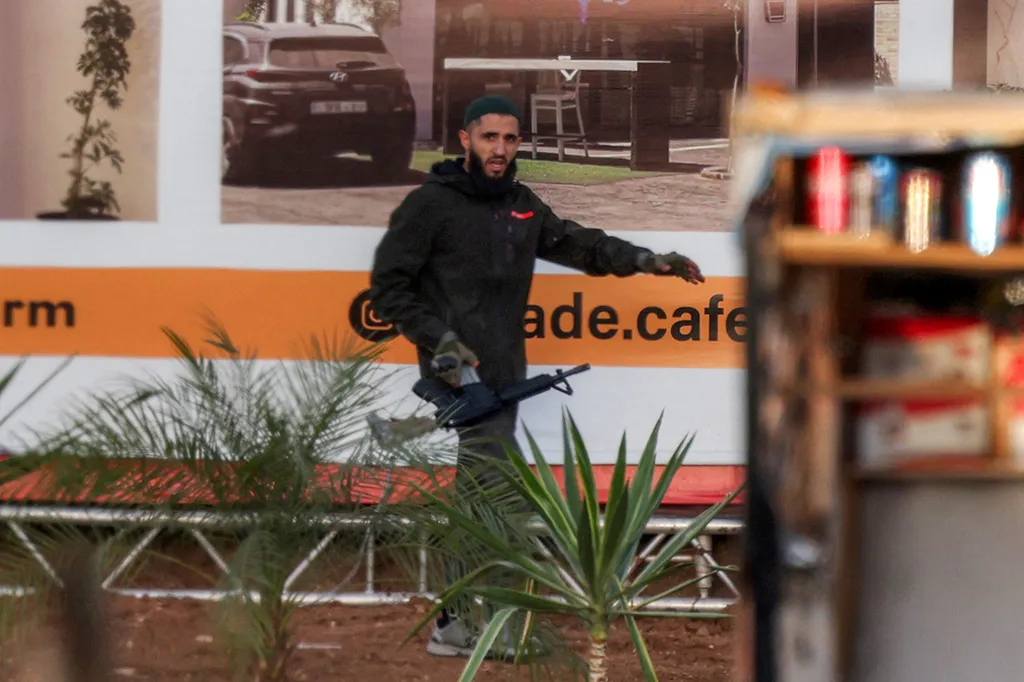 An armed Palestinian man walks with an assault rifle during a fire exchange with Israeli forces in the West Bank.