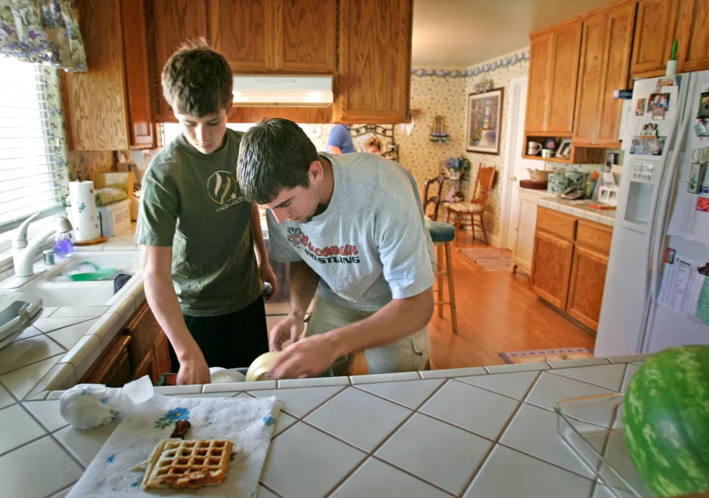 Green Bay Packers quarterback Aaron Rodgers and his younger brother Jordan put away dishes in a kitchen.