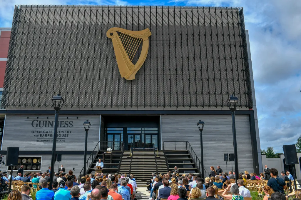 A crowd sits facing a speaker at the ribbon-cutting ceremony for the Guinness Open Gate Brewery & Barrel House in Halethorpe, Maryland.