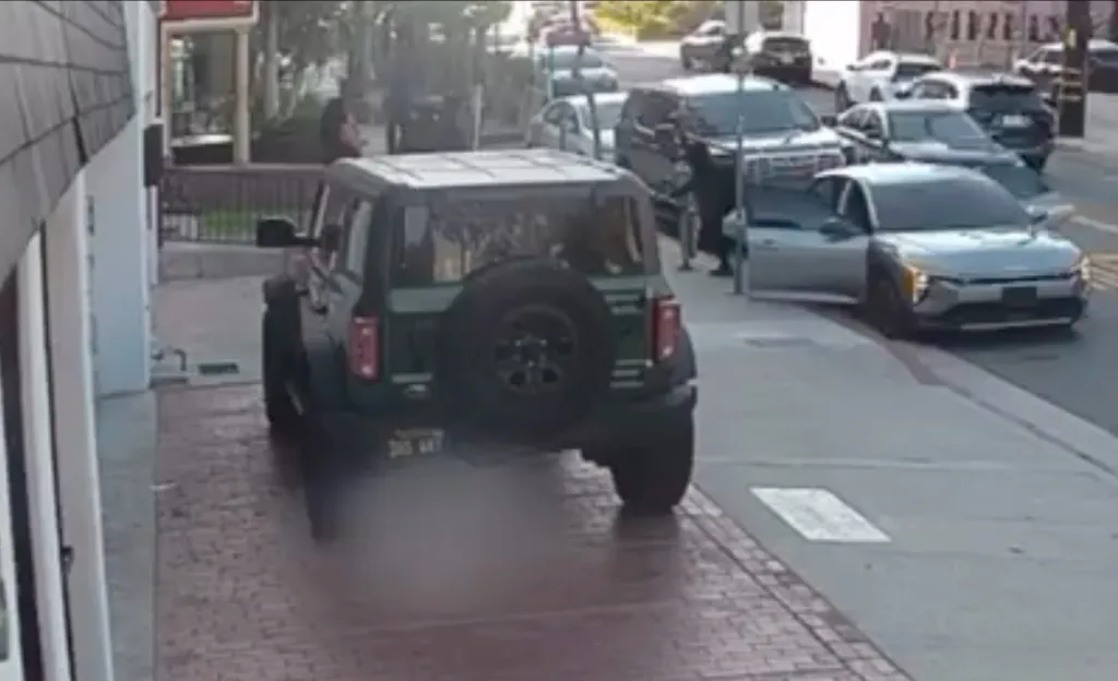 A green SUV and other vehicles parked on a city street where gunfire erupted during a robbery in West Hollywood.