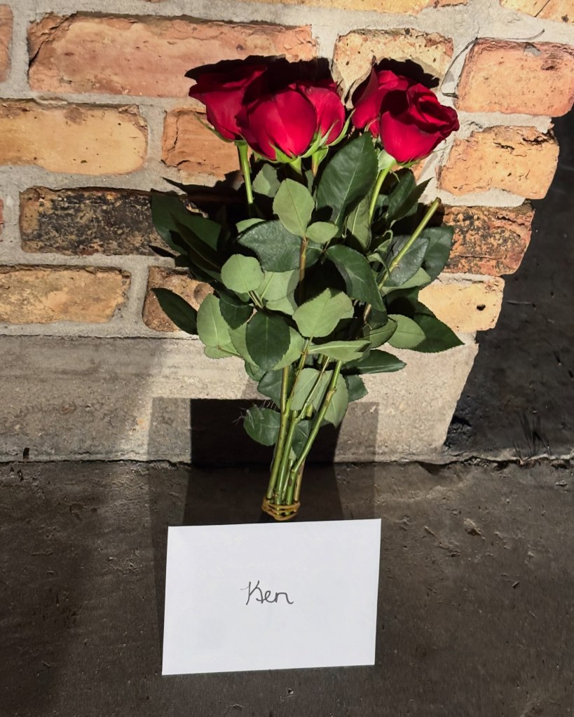 A bouquet of red roses with a note reading 
