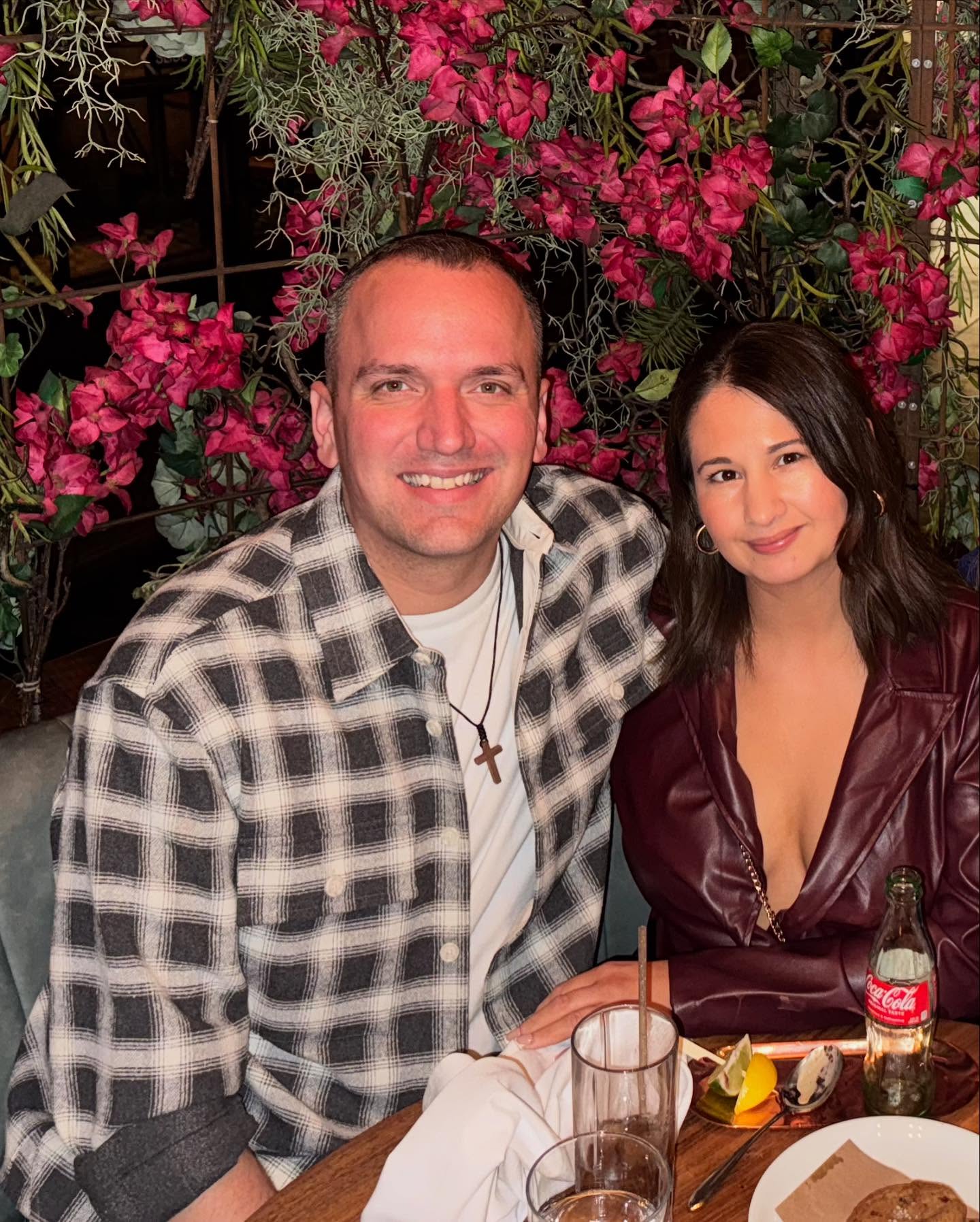 Gypsy Rose Blanchard and Ken Urker posing together in front of a backdrop of pink flowers.
