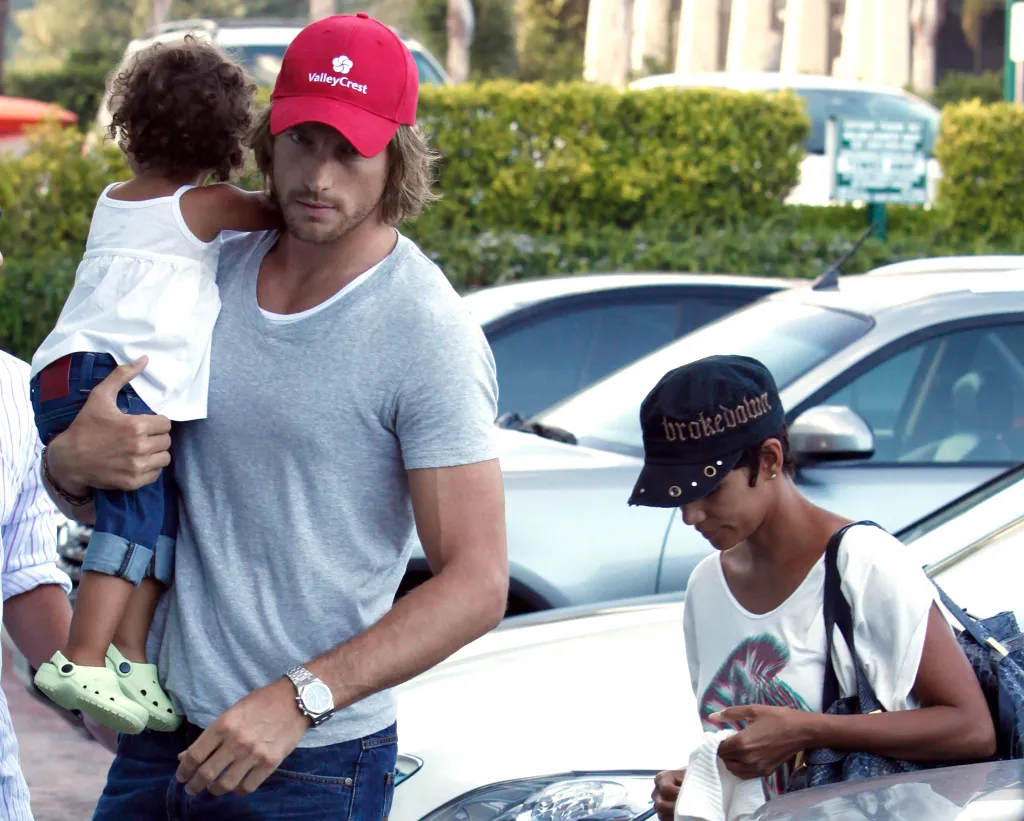 Halle Berry, in a black cap and white T-shirt, and Gabriel Aubry, in a grey T-shirt and red baseball cap, and baby Nahla in a white top and jeans, in Malibu.