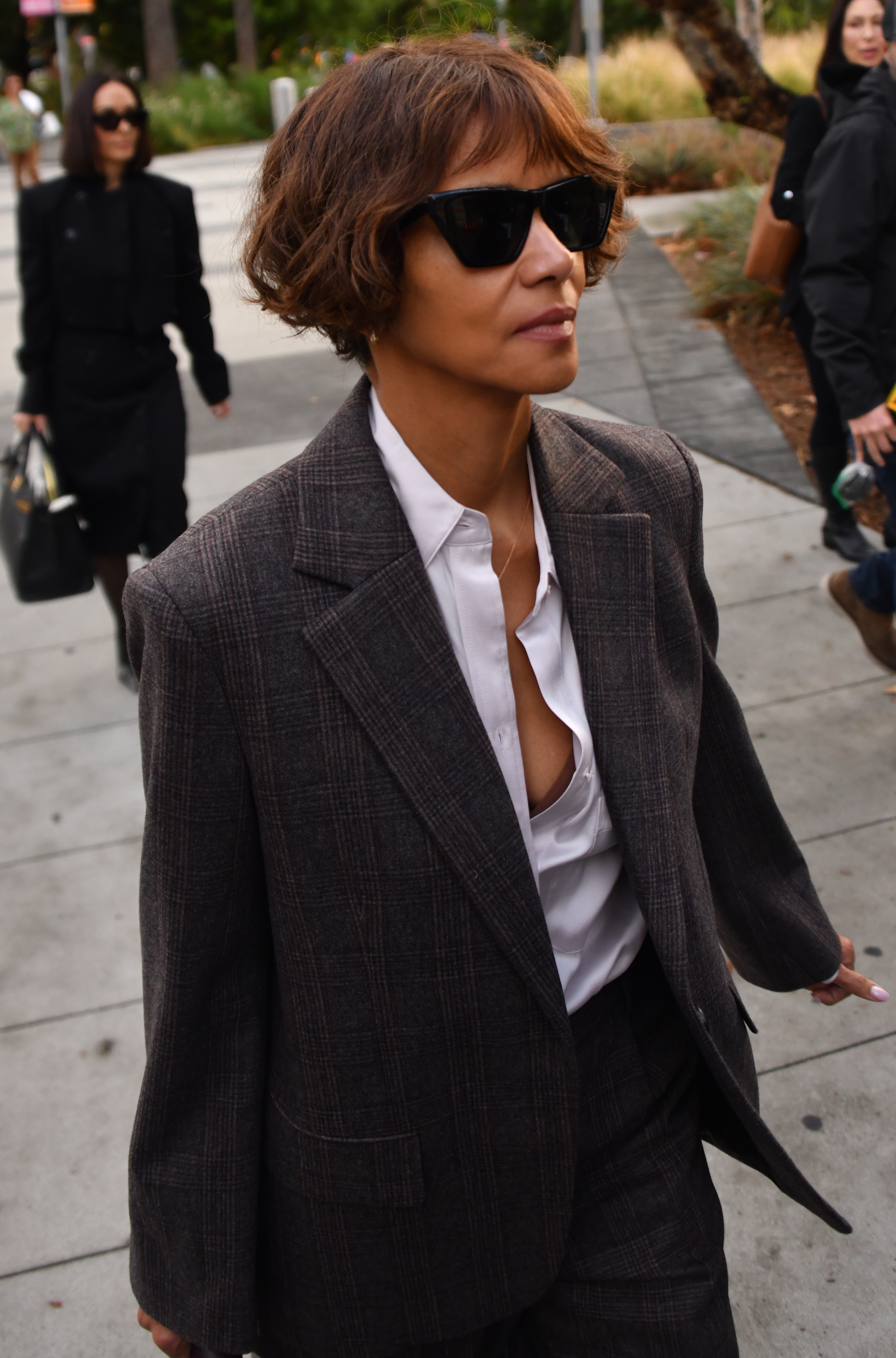 Halle Berry wearing a dark plaid suit, a white shirt, and sunglasses outside the courthouse.
