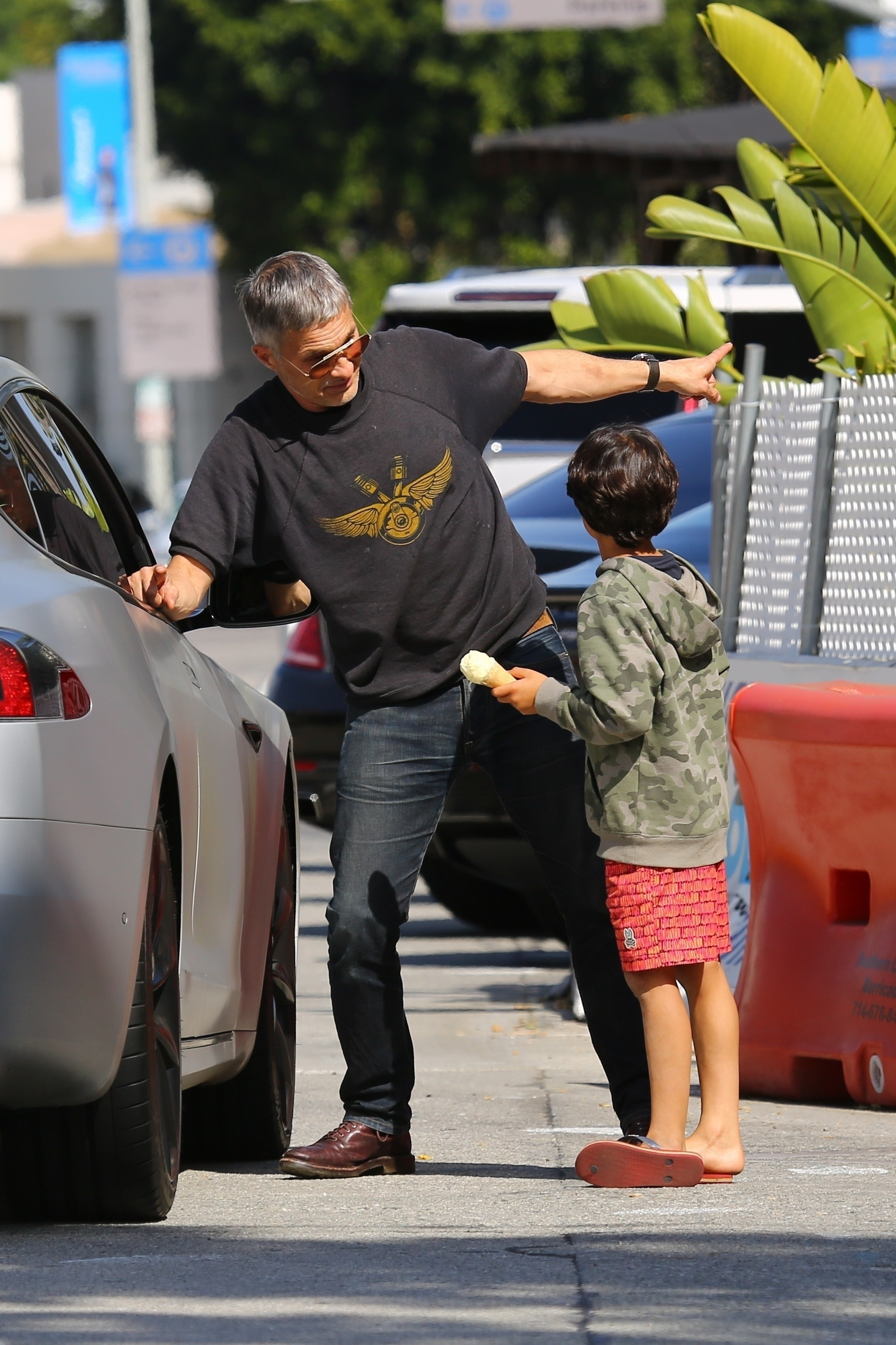 Olivier Martinez and his son Maceo stand by a car outdoors, with Olivier pointing and Maceo holding an ice cream cone.