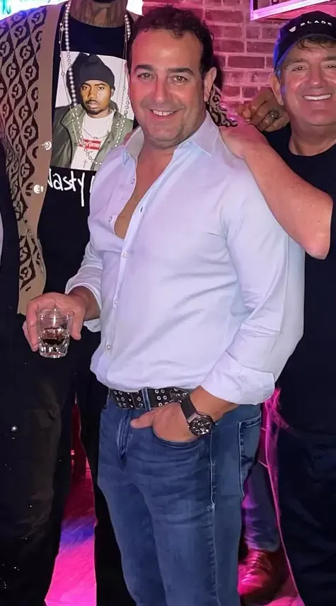 Real estate developer Mangiameli holds a glass of liquor while posing with friends.