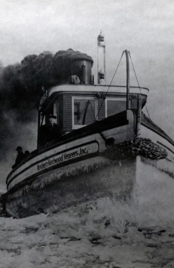 Historic black and white photograph of the A.H. Pitz, a steam-powered tugboat, operating in icy waters with smoke billowing from its smokestack.