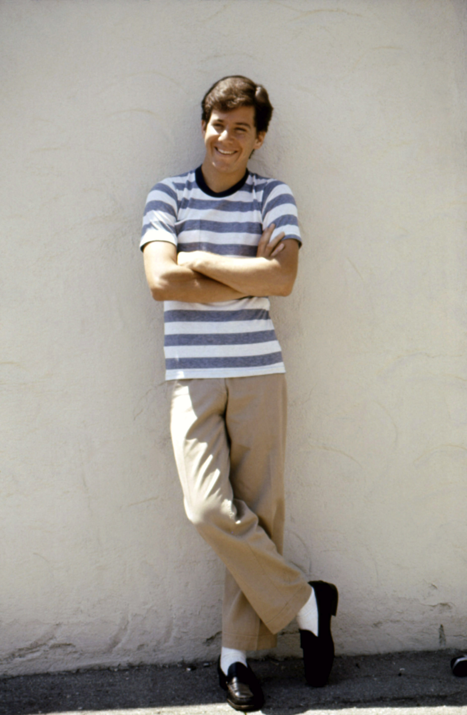 Portrait of Anson Williams leaning against a wall with his arms crossed.