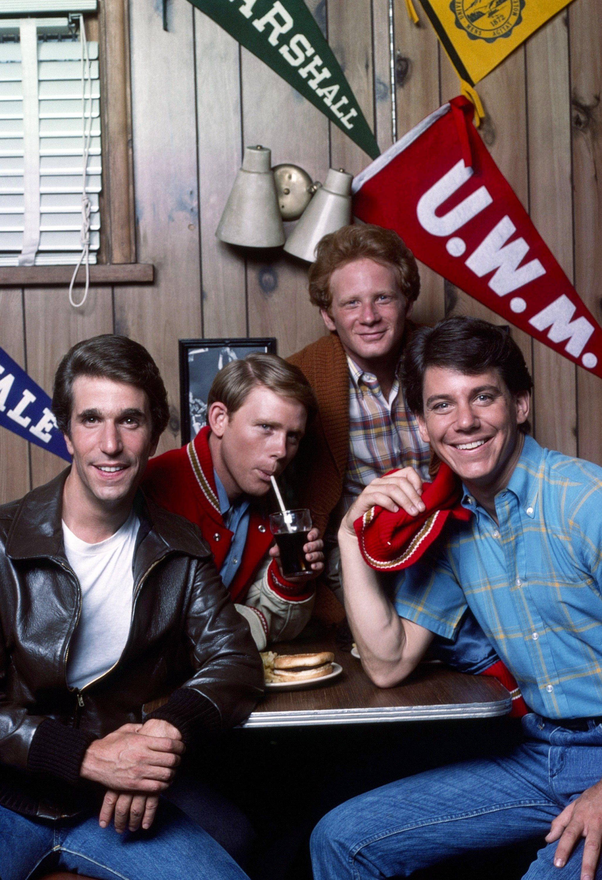A promotional photo of Henry Winkler, Ron Howard, Don Most, and Anson Williams from the television sitcom Happy Days, sitting together in a diner.