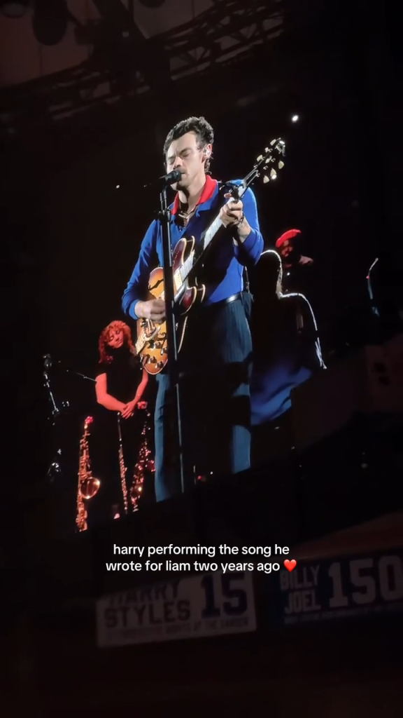 Harry Styles performing on stage with a guitar.