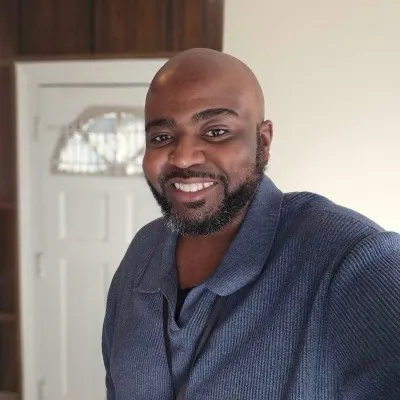 Hassan Jihad Ibn Kariem smiling indoors.