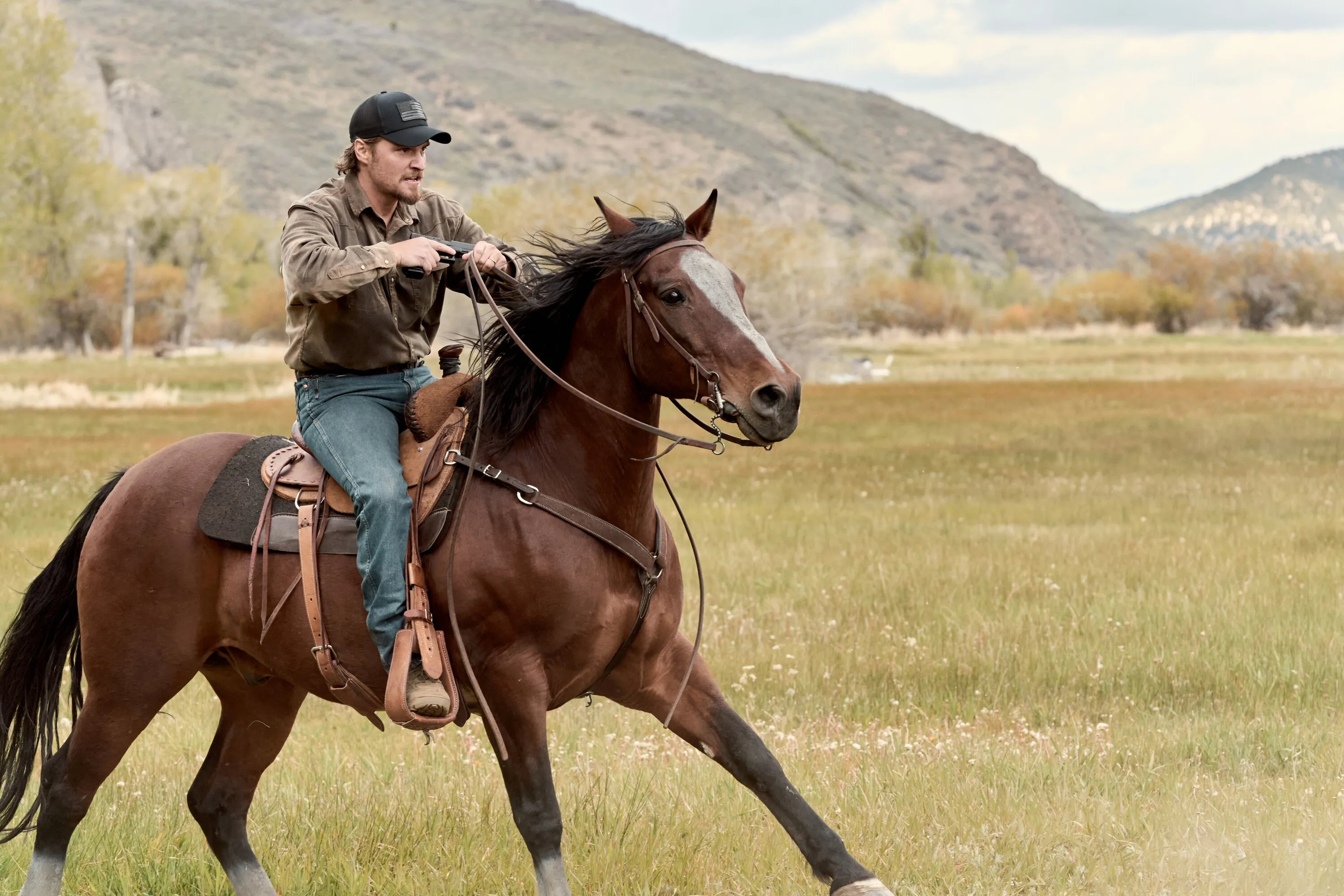 Luke Grimes as Kayce Dutton riding a horse across a field in the series Marshals.