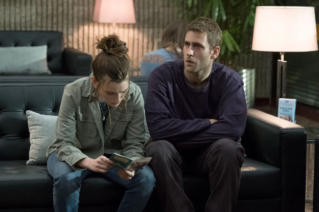 Victoria Pedretti and Oliver Jackson-Cohen sitting on a sofa in The Haunting of Hill House.