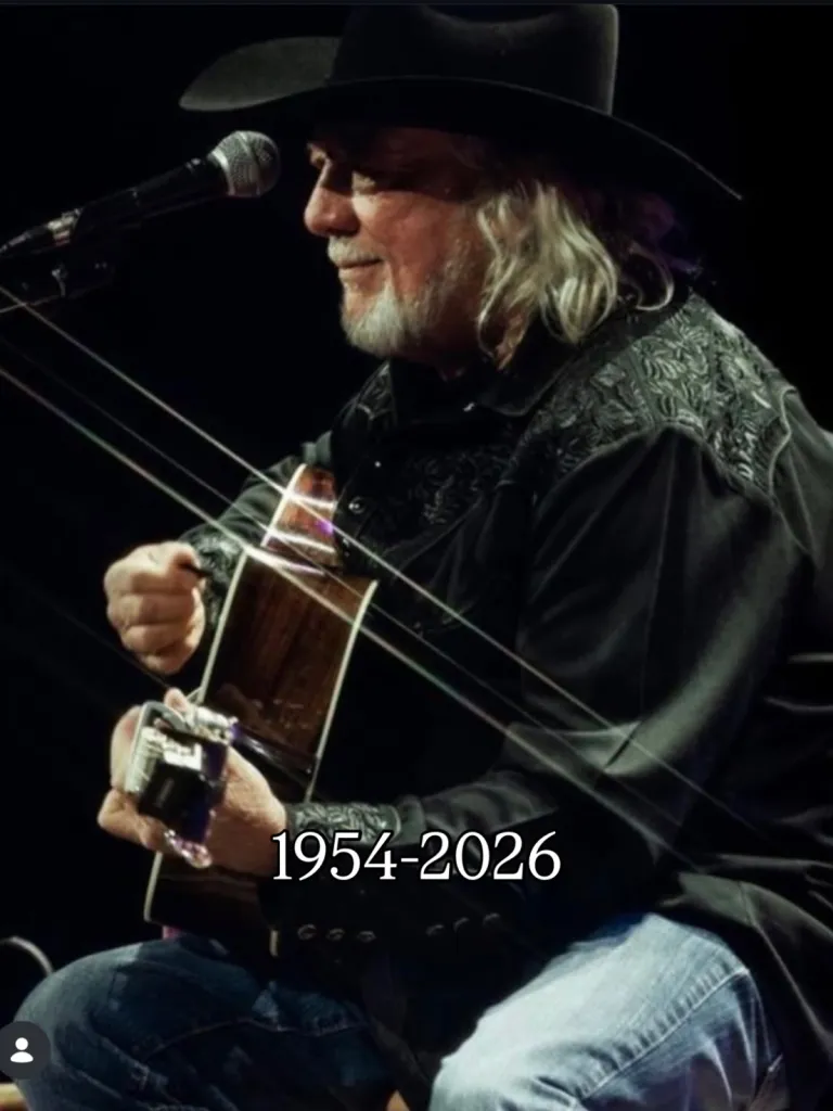 Country music singer wearing a cowboy hat and playing an acoustic guitar on stage.