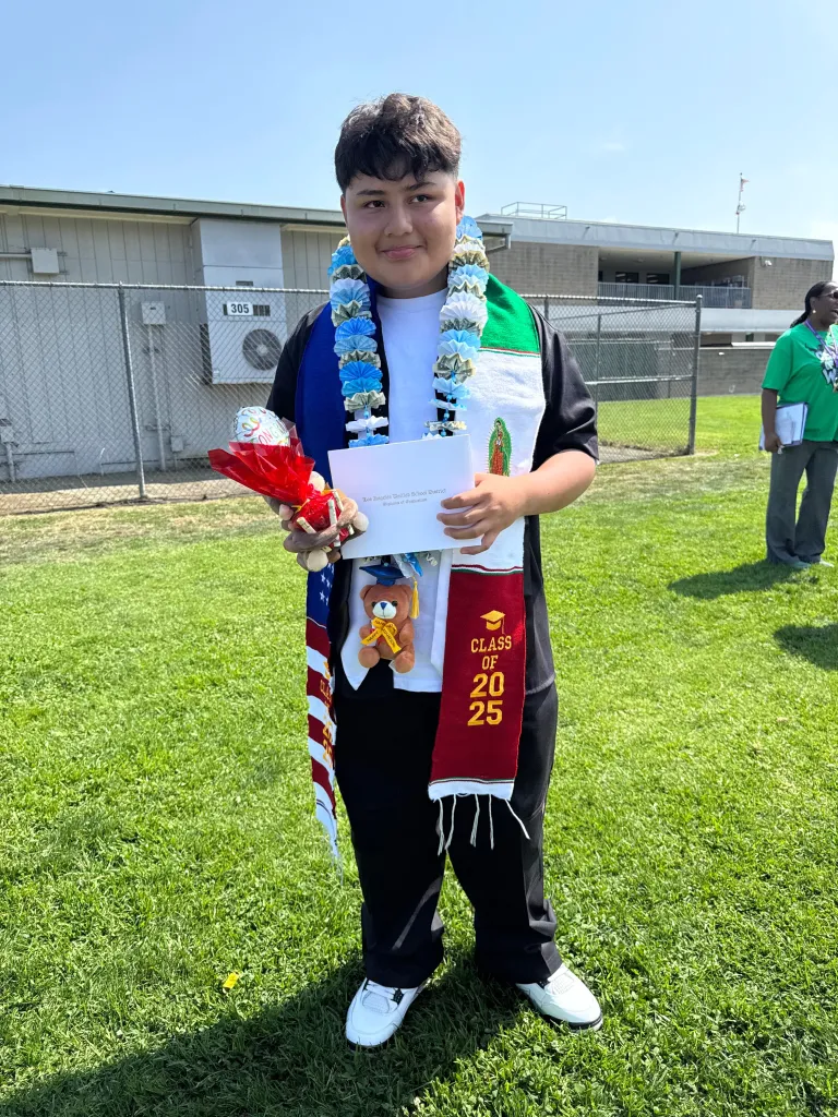 Hernan Martinez holding a diploma and a gift at a graduation.