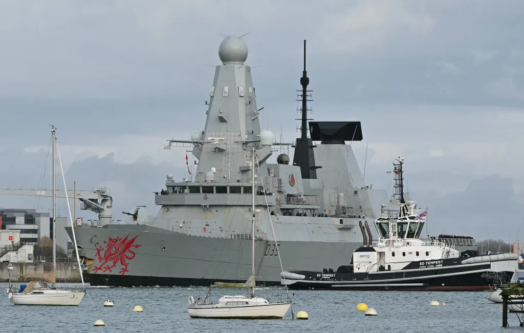 The Royal Navy Type 45 destroyer HMS Dragon is guided by a Serco tugboat as it departs Portsmouth.