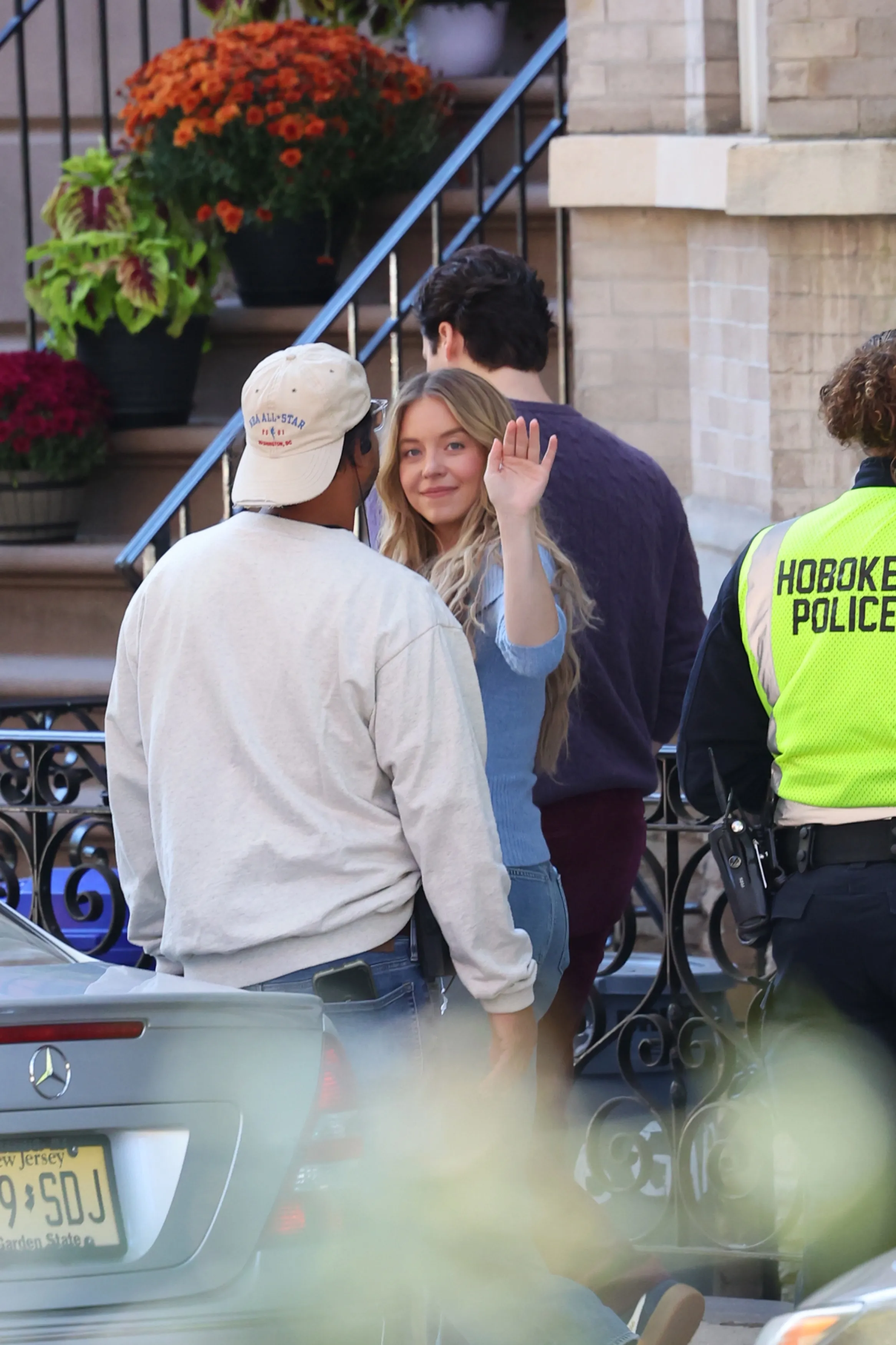 Sydney Sweeney waves to onlookers while filming 