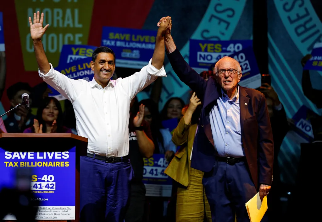 US Representative Ro Khanna and US Senator Bernie Sanders hold hands at a rally in support of Proposition 40 and in opposition to Propositions 41 and 42.