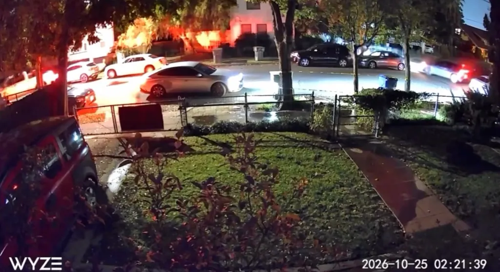 Security camera footage capturing a street scene at night outside a house where a shooting occurred during a music video shoot.
