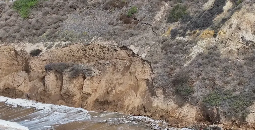 A large crack running down a dirt cliff next to the Pacific Coast Highway.