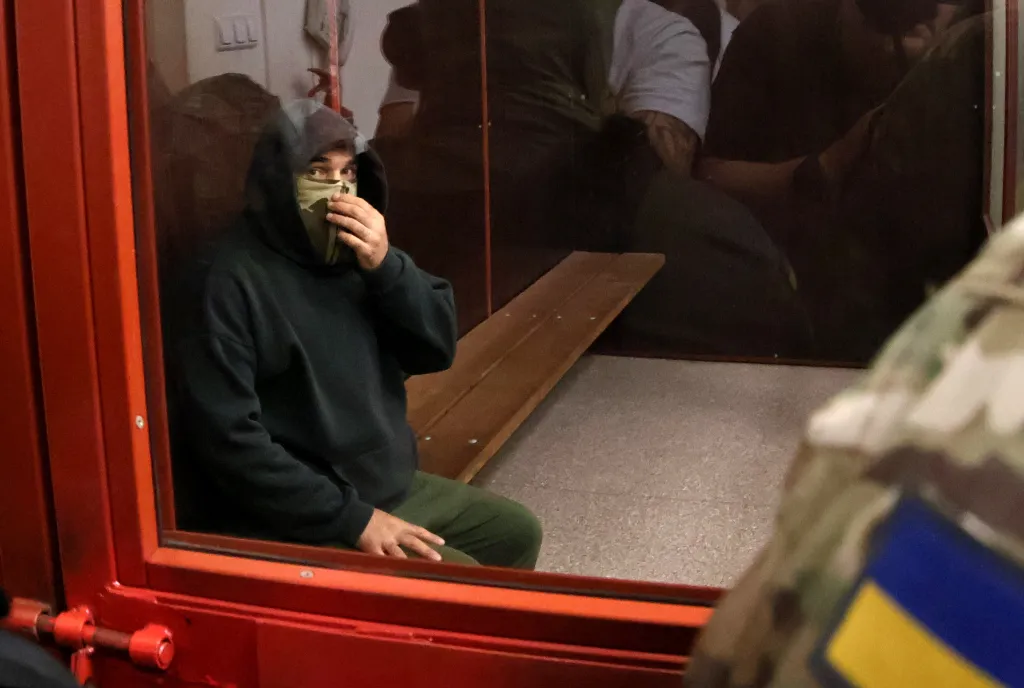 Former SBU officer Vitalii Zhykovych, a suspect in the murder case of Anastasiia Berezovska, sits in a glass-walled defendant's cage during a court hearing in Kyiv.