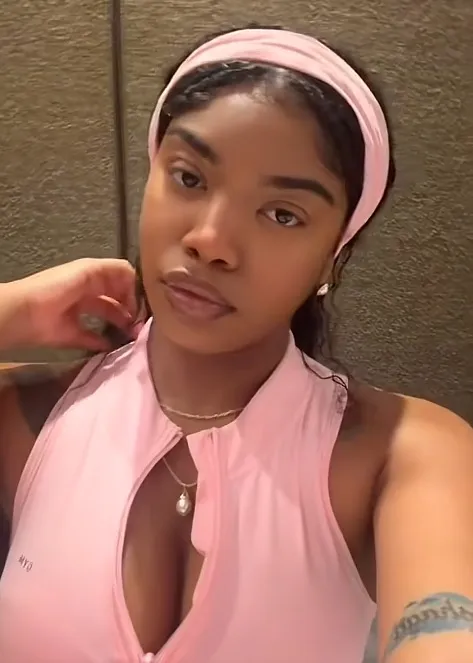 A young woman wearing a pink headband and a pink athletic top with a front zipper.