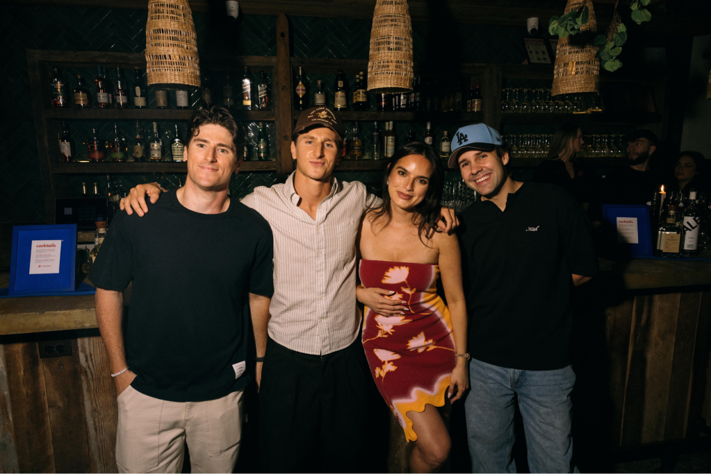 Four people pose in front of a bar counter.