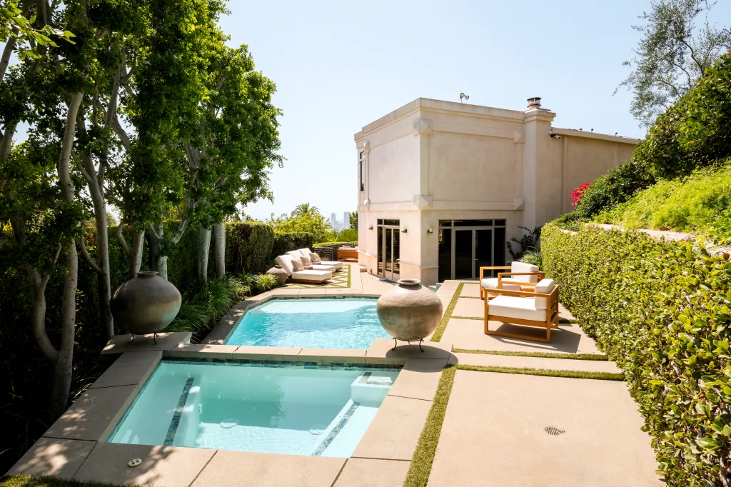 Exterior view of Dolly Parton's Los Angeles home featuring a pool, spa, and lounge area surrounded by lush greenery.