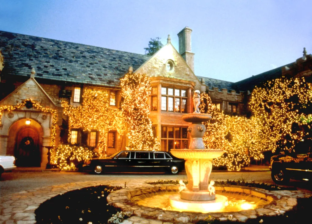 Hugh Hefner's Playboy Mansion decorated with lights, featuring a limousine and a fountain in the front courtyard.