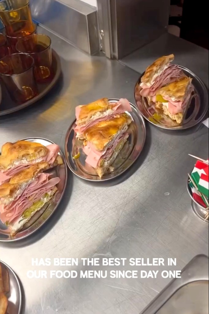 Three plates of Mortadella Focaccia sandwiches on a metal counter.