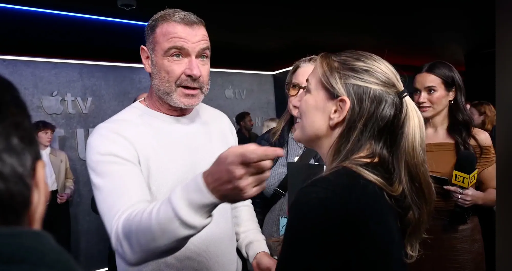 Liev Schreiber pointing and speaking to a reporter at an event.