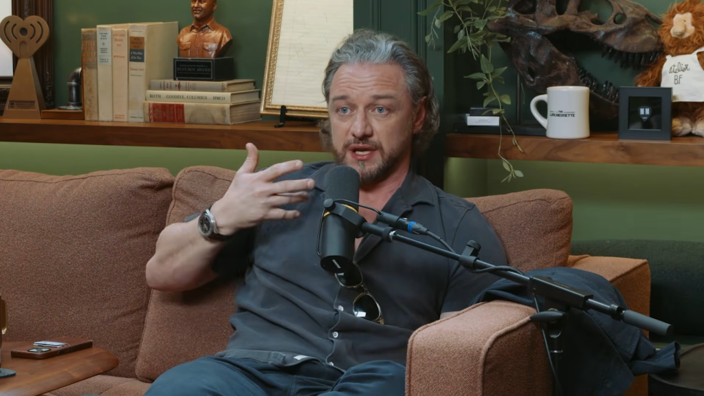 James McAvoy sitting on a brown couch and talking into a microphone.