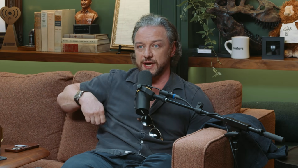 James McAvoy sitting on a brown couch speaking into a microphone.