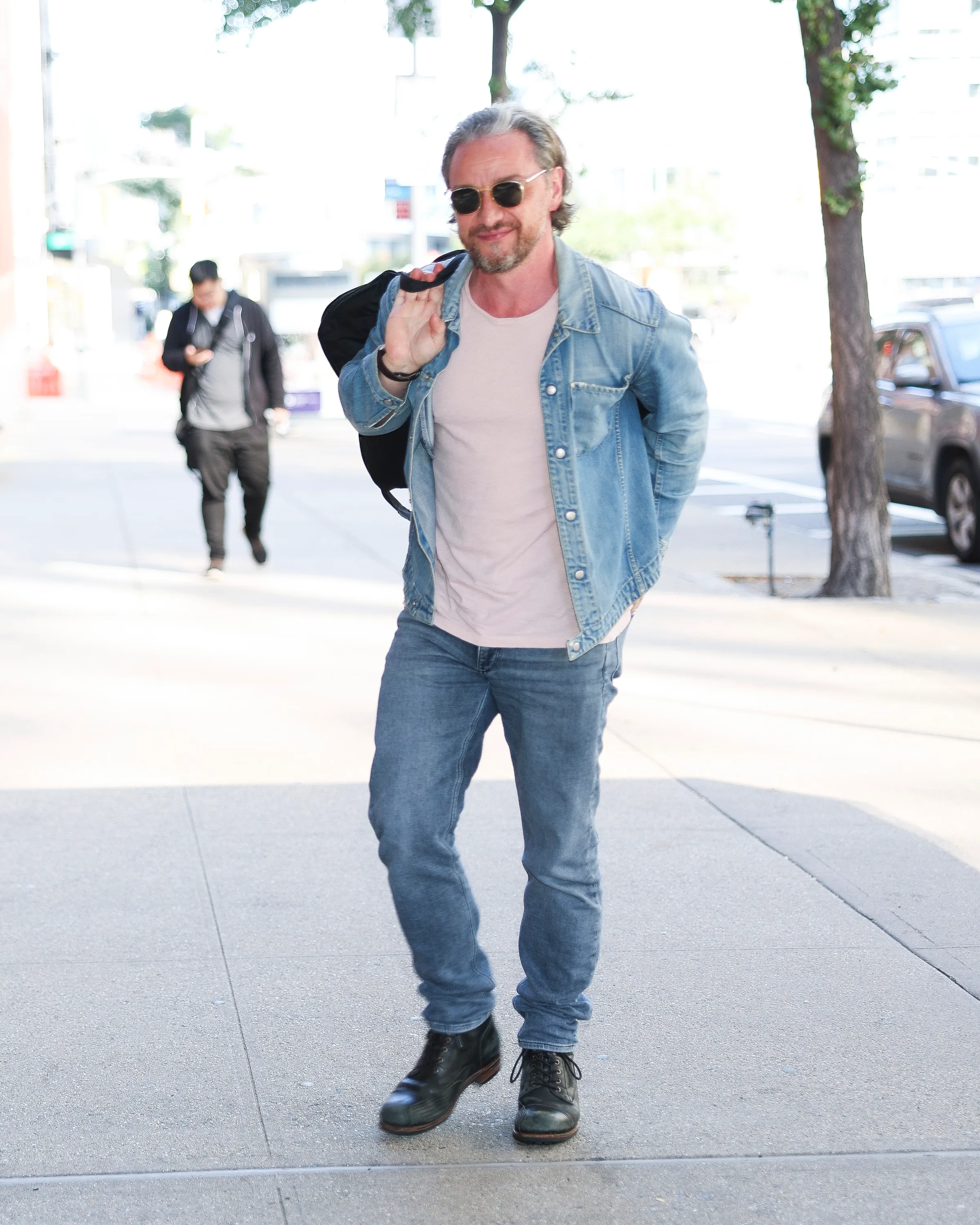 James McAvoy walking on a New York City sidewalk in casual denim attire.