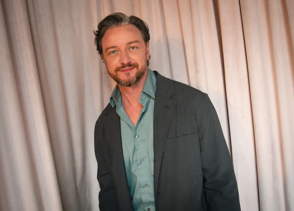 James McAvoy poses in front of a curtain backdrop.