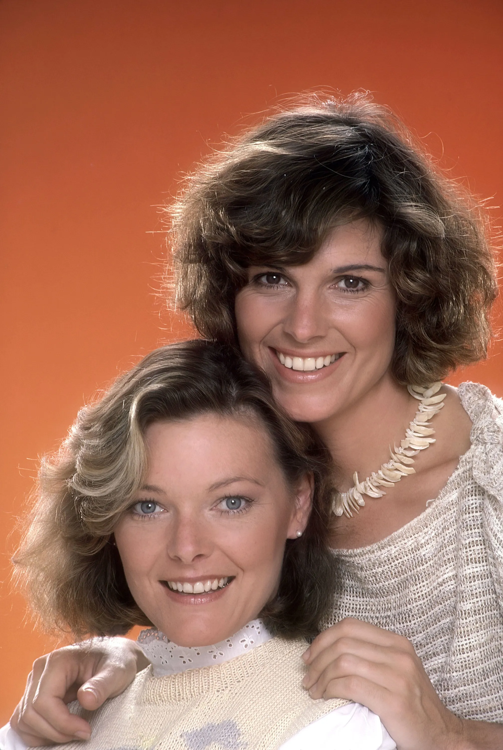 Jane Curtin and Susan Saint James smiling against an orange background.