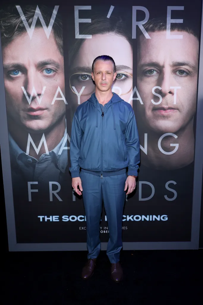 Jeremy Strong stands in front of a movie poster for 