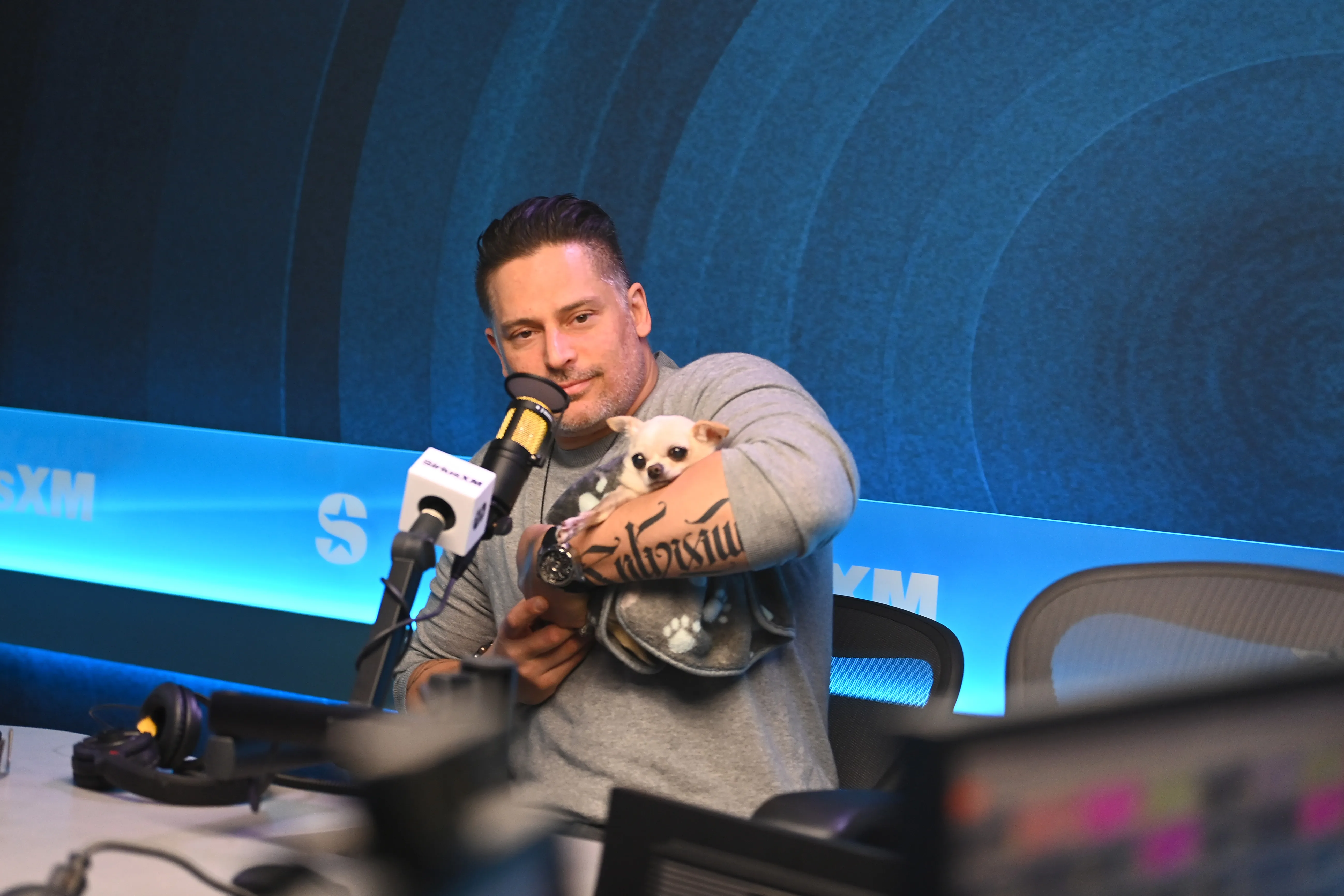 Joe Manganiello holding a dog in a SiriusXM studio.