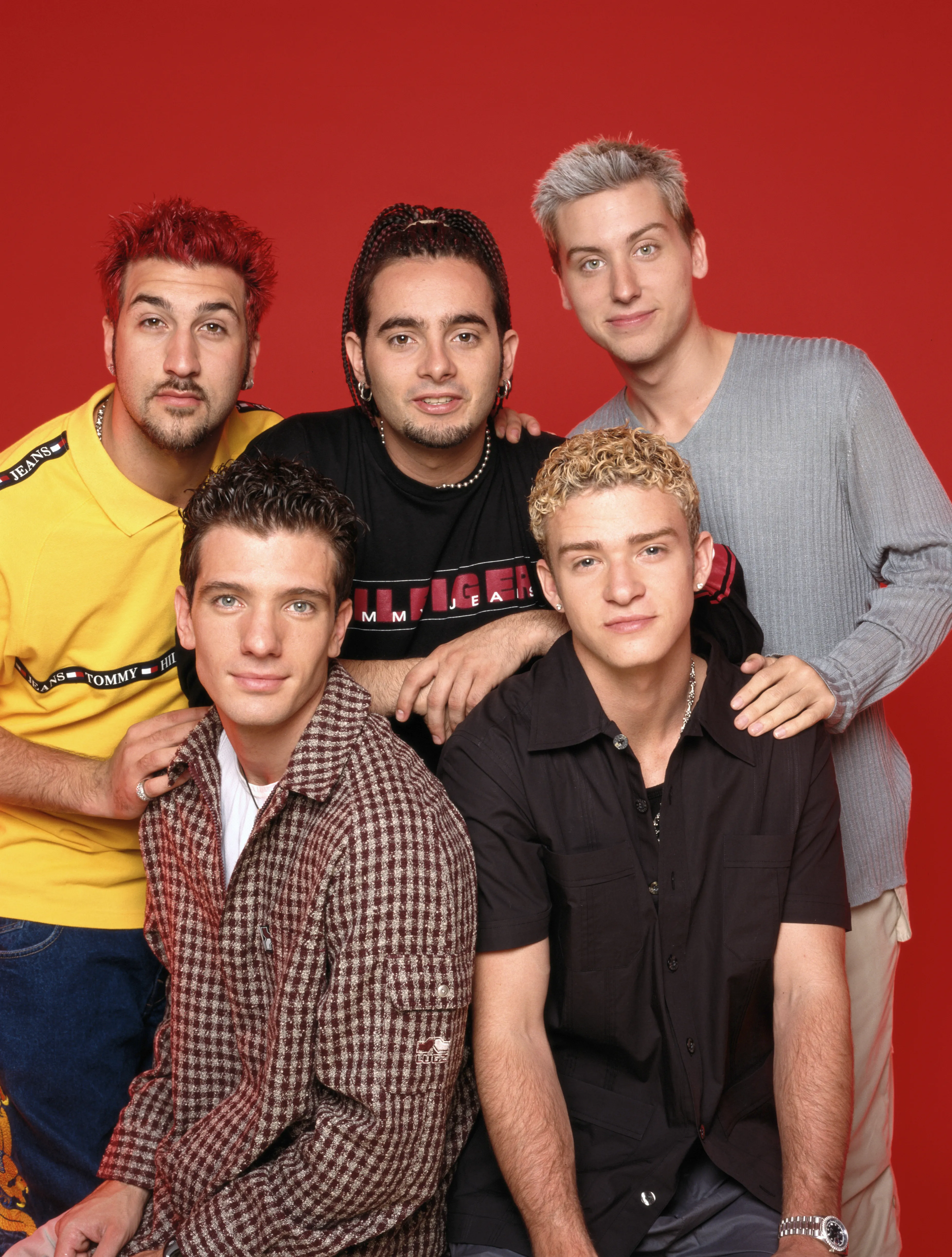 Studio portrait of the American boy band NSYNC against a red background.