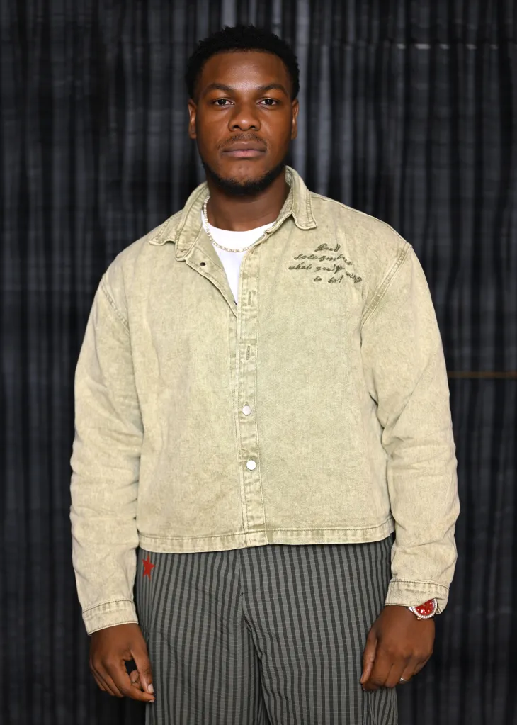 John Boyega standing against a dark backdrop.