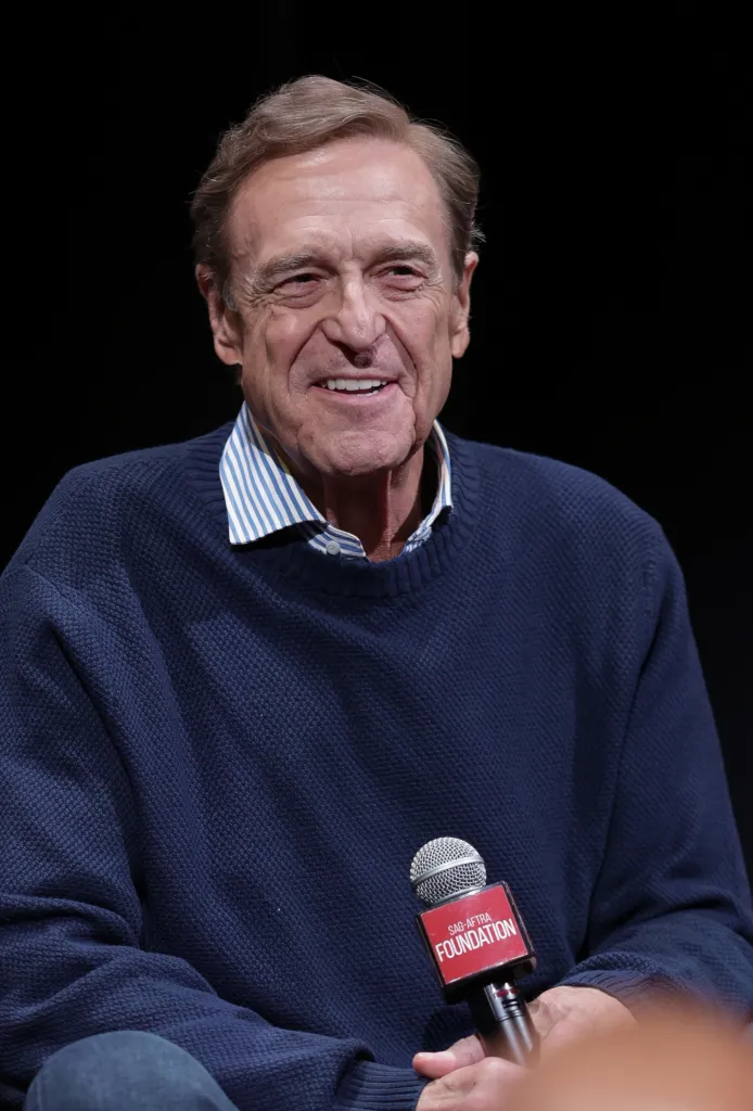John Goodman smiles while holding a SAG-AFTRA Foundation microphone at an event in New York City.