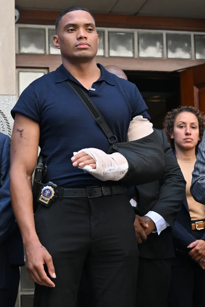 NYPD Detective Jose Mercedes stands with his arm in a sling and bandages following a stabbing attack.